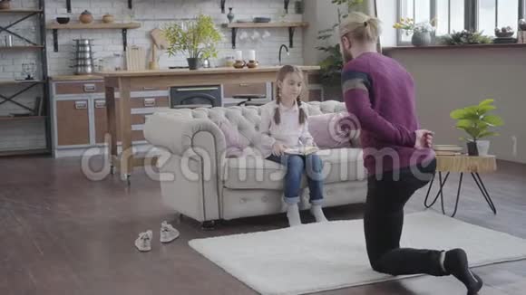 成年白种人的父亲单膝站立牵着女儿的手十几岁的女孩把书和跳舞视频的预览图
