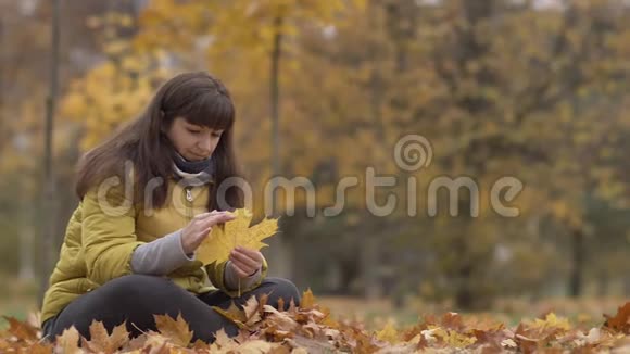 秋天女人手里拿着黄色的枫叶想着什么慢悠悠的动作视频的预览图