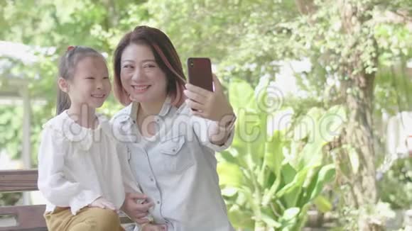 亚洲开朗的母亲和女儿坐在花园里视频的预览图