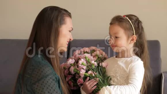 快乐的女孩送花在家拥抱她的母亲妈妈一天的概念视频的预览图