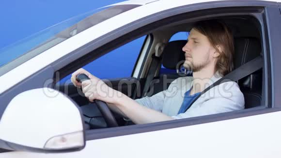 快乐有趣的人在车里听音乐和跳舞年轻的司机坐在蓝底白色的车里视频的预览图