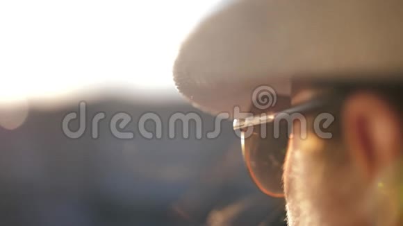 戴墨镜的女人看着远处夕阳的特写慢镜头视频的预览图