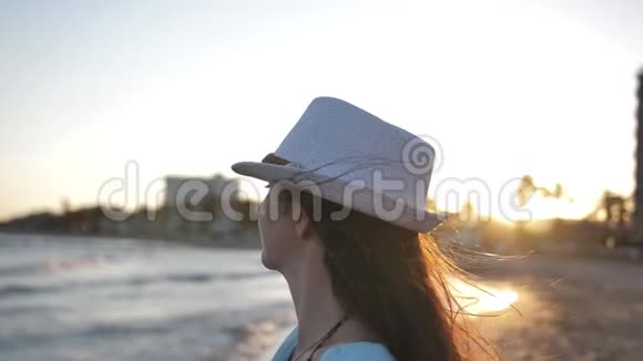 女人在海边欣赏日落举起双臂微笑旅行理念视频的预览图