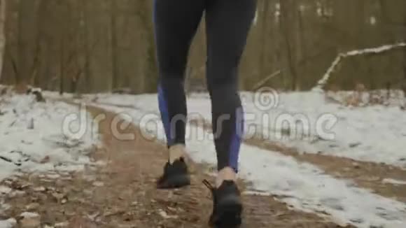 女足在公园里奔跑靠近后景把跑步的腿收起来穿着黑色和蓝色的腿和运动鞋的女人慢跑视频的预览图