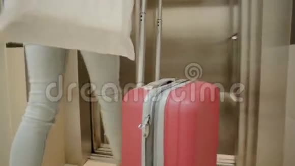 乘坐旅行套装和旅行袋进入电梯的女游客贴身脚视频的预览图