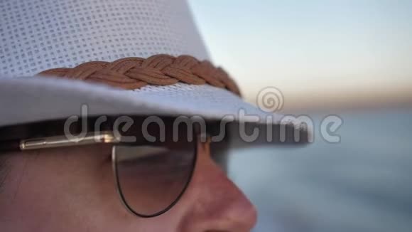 一个戴着太阳镜和帽子的女人的特写镜头看着大海视频的预览图