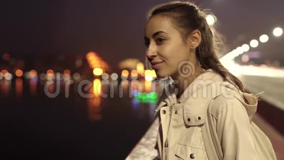 慢动作的美丽微笑的年轻女子走在户外的夜晚城市视频的预览图