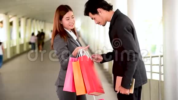 网上购物网站上女人拿着购物袋在零售购物中心购买产品情侣一起买东西视频的预览图