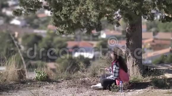 坐在山顶树下听音乐的女人视频的预览图