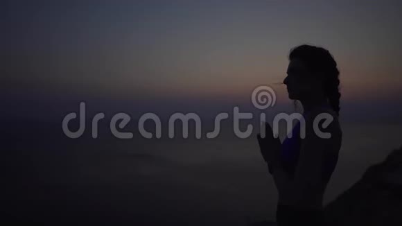年轻的白种人女孩从事呼吸练习在夕阳的映照下在海洋上沉思视频的预览图