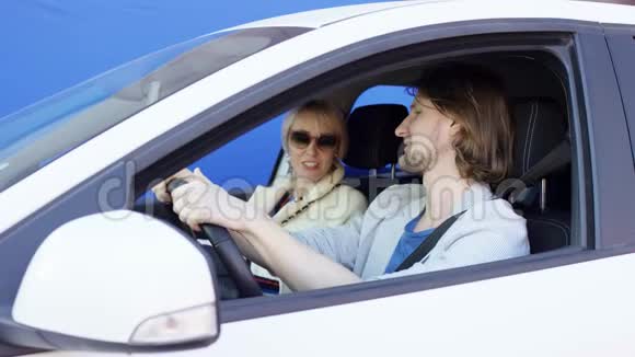 Brunette男子和戴墨镜的金发美女坐在白色的车里背景是彩色钥匙女性视频的预览图