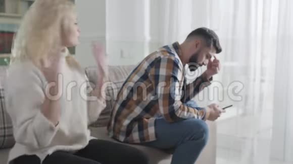 一个漂亮的年轻女人对坐着智能手机的男人大喊大叫对丈夫不满妻子视频的预览图