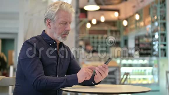 愤怒的老人在咖啡馆里讲智能电话视频的预览图