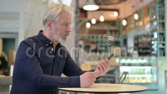 老人在咖啡厅讲智能电话视频的预览图