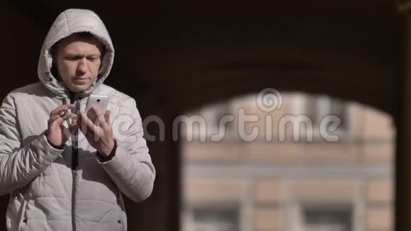 冬天戴着兜帽的人站在街上用电话视频的预览图