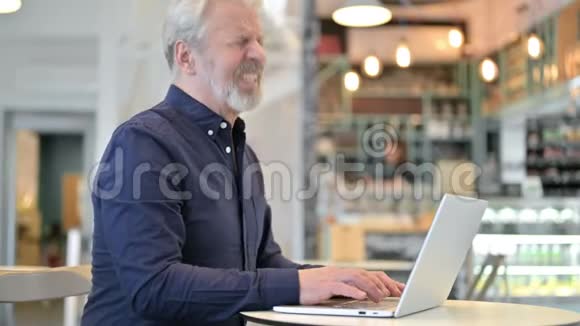 背疼老人在咖啡厅用笔记本电脑视频的预览图