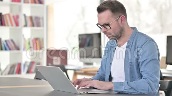戴眼镜的年轻人因丢失而心烦意乱使用笔记本电脑视频的预览图