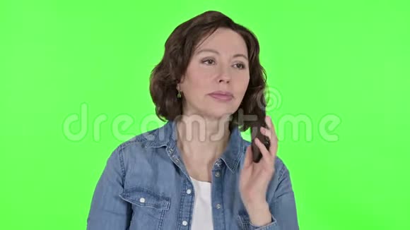 老女人在绿色彩色钥匙背景上讲智能手机视频的预览图