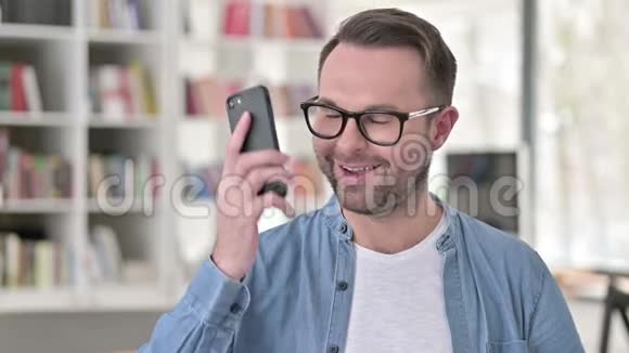 戴眼镜的年轻人的电话交谈谈判视频的预览图
