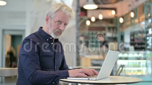 老人在咖啡厅里用手提电脑视频的预览图