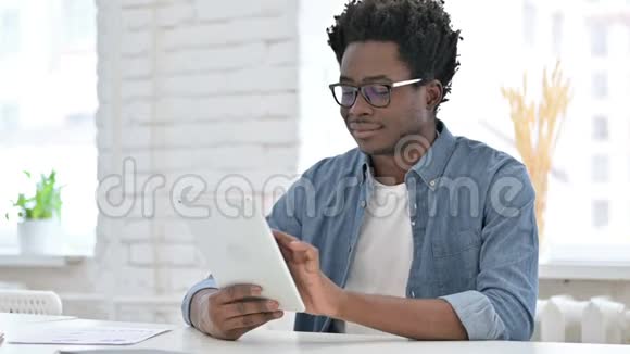 年轻的非洲男人在办公室里用平板电脑视频的预览图