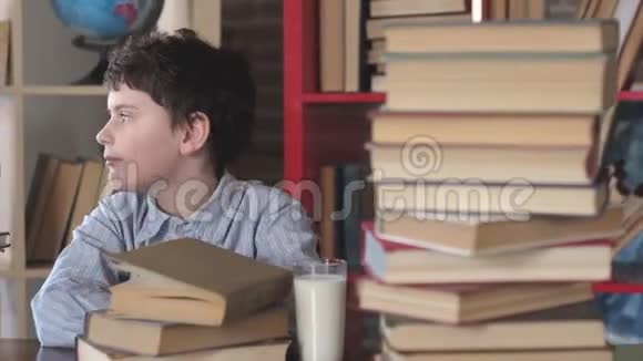 男生坐在家里的办公桌上吃带牛奶的饼干学生早餐视频的预览图