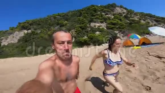 一对夫妇在海滩上奔跑跳进海水里视频的预览图