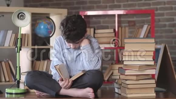 读书男生盘腿坐在书桌上读打开的课本视频的预览图
