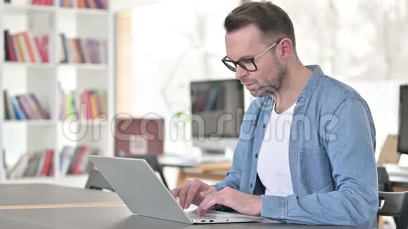 戴眼镜的年轻人在笔记本电脑上工作视频的预览图