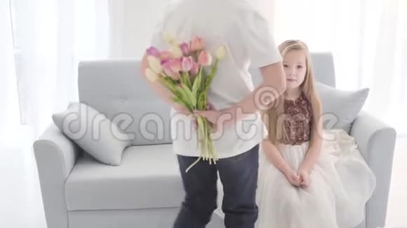 白人男孩穿着白色T恤和牛仔裤来到一个漂亮的女孩与郁金香花束令人惊讶的孩子视频的预览图