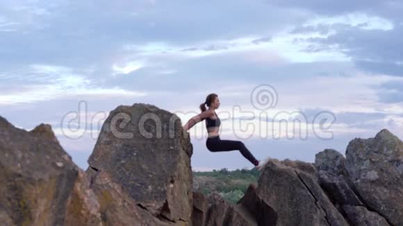 运动的女人在山崖上练习瑜伽和体操有美丽的景观背景健康视频的预览图