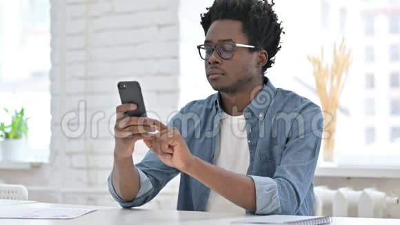 年轻的非洲男人在智能手机上滚动视频的预览图