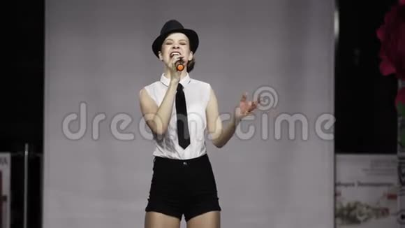 美丽的女孩黑帽子可爱的唱歌麦克风优雅的移动步道女歌手视频的预览图