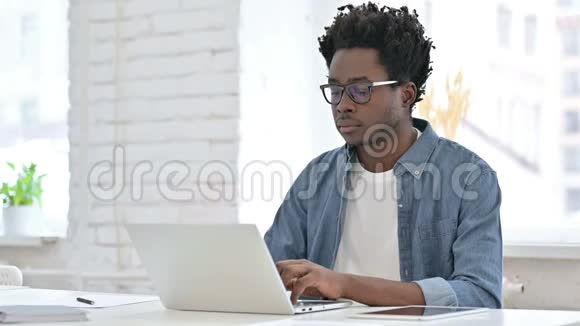 年轻的非洲男人在办公室的笔记本电脑上得到惊喜视频的预览图
