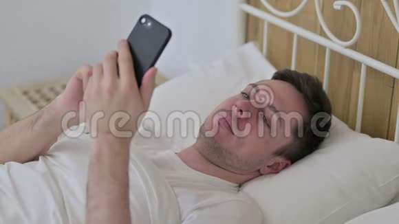 在床上使用智能手机的年轻人视频的预览图