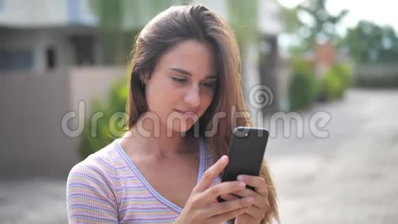 迷人的年轻女性在阳光明媚的城市街道上散步与朋友聊天在户外使用手机城市视频的预览图