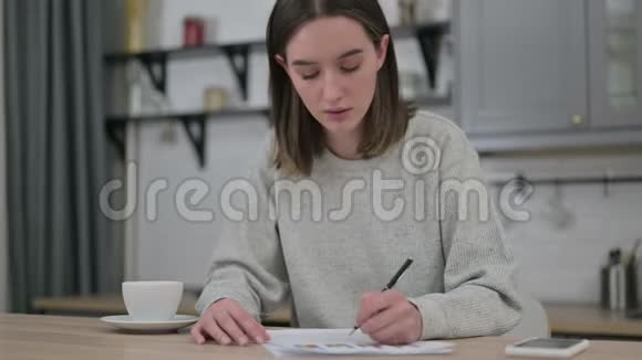 青年妇女在客厅阅读财务文件视频的预览图