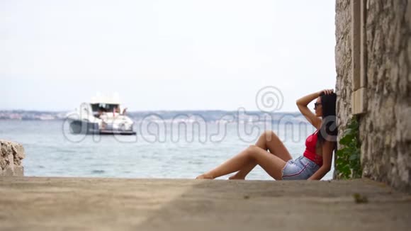 美丽的女孩穿着泳衣坐在岸边迷人的女孩坐在岸边慢动作克罗地亚视频的预览图