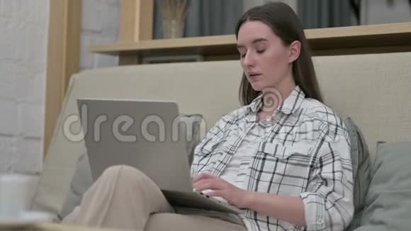 疲惫的年轻女子坐在沙发上背痛视频的预览图