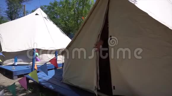 夏天穿着黑色比基尼的年轻性感女人从白色的大帐篷里出来在闷热的地方视频的预览图