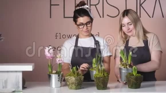 一家花店里的两个花店女孩用花盆装饰花视频的预览图