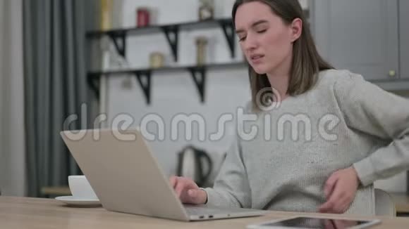 年轻女子手提电脑及背部疼痛视频的预览图