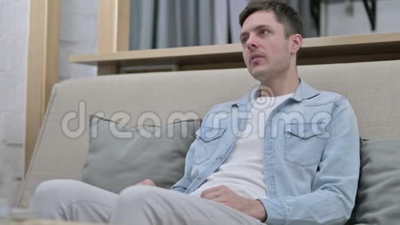 疲惫的年轻人坐在沙发上背疼视频的预览图