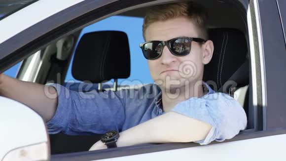 年轻人坐在他的白色车里戴着蓝纱的背景他靠在车窗上他是视频的预览图