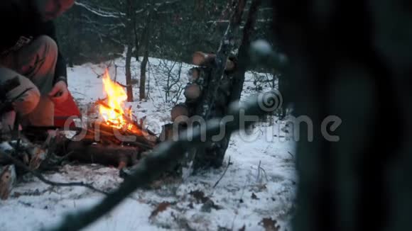 游客在靠近反光镜的冬季森林里生火视频的预览图