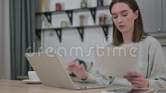 专注的年轻女性使用笔记本电脑和做纸工视频的预览图