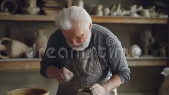 由熟练的工匠专业陶工在抛轮上成型粘土和制作壶灰头胡子视频的预览图