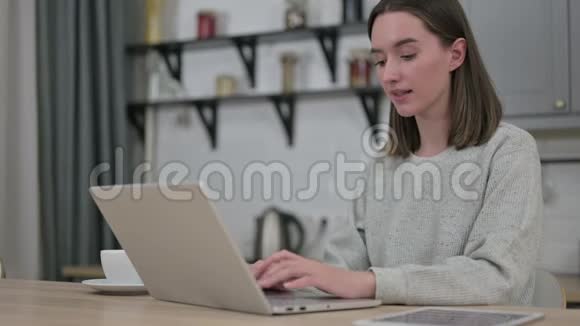 在客厅的笔记本电脑上丢失的年轻女子视频的预览图