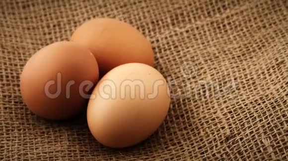 三个新鲜的棕色鸡蛋旋转的麻布背景视频的预览图