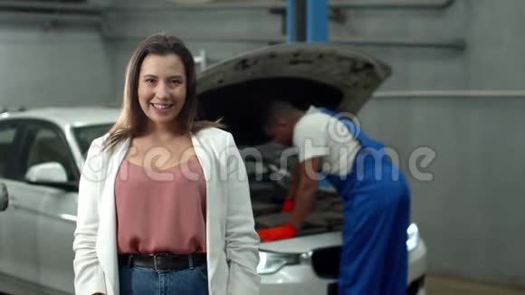 动作慢机械师修理汽车女人对着镜头微笑视频的预览图